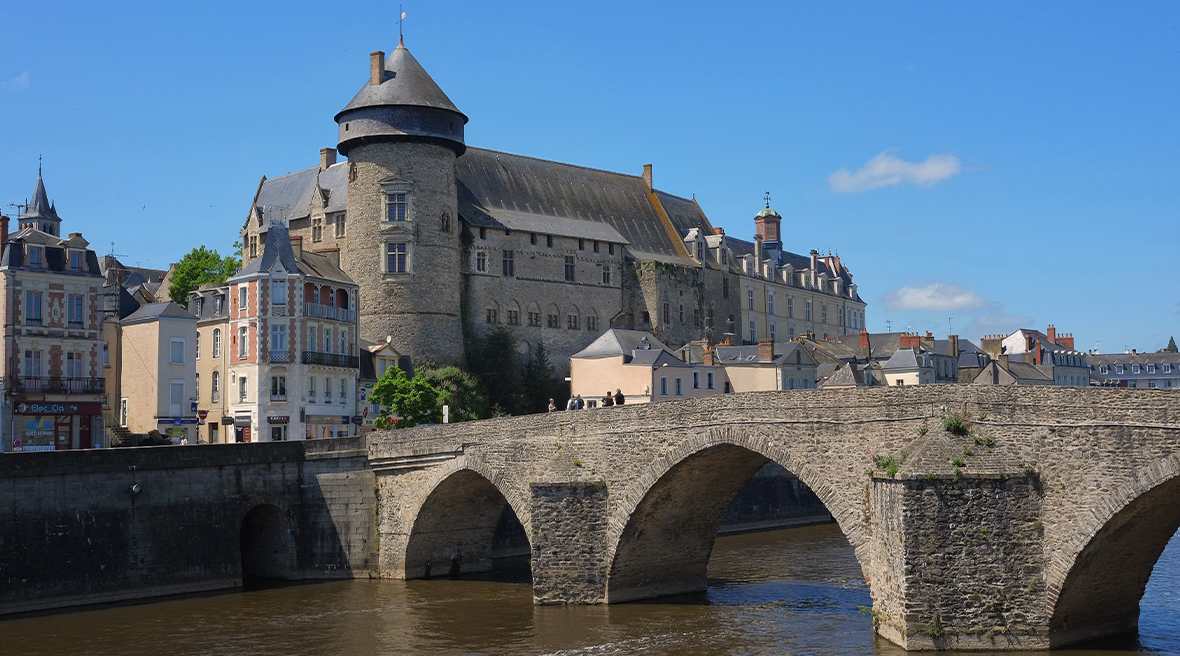 A stone arched bridge stretching over a river with a town on one side